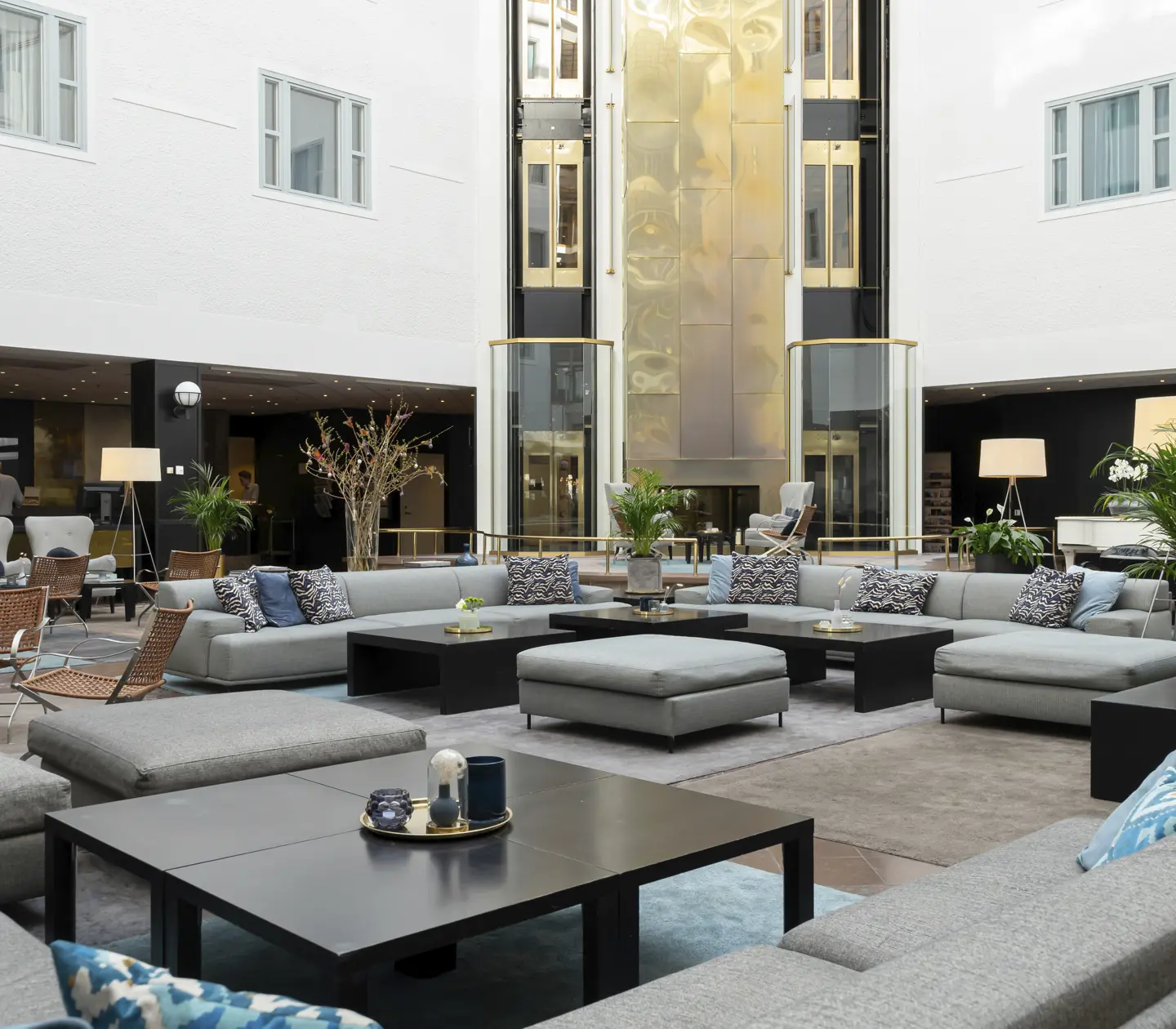 Elegant and spacious hotel lobby with modern decor, seating areas in a neutral color scheme and natural light.