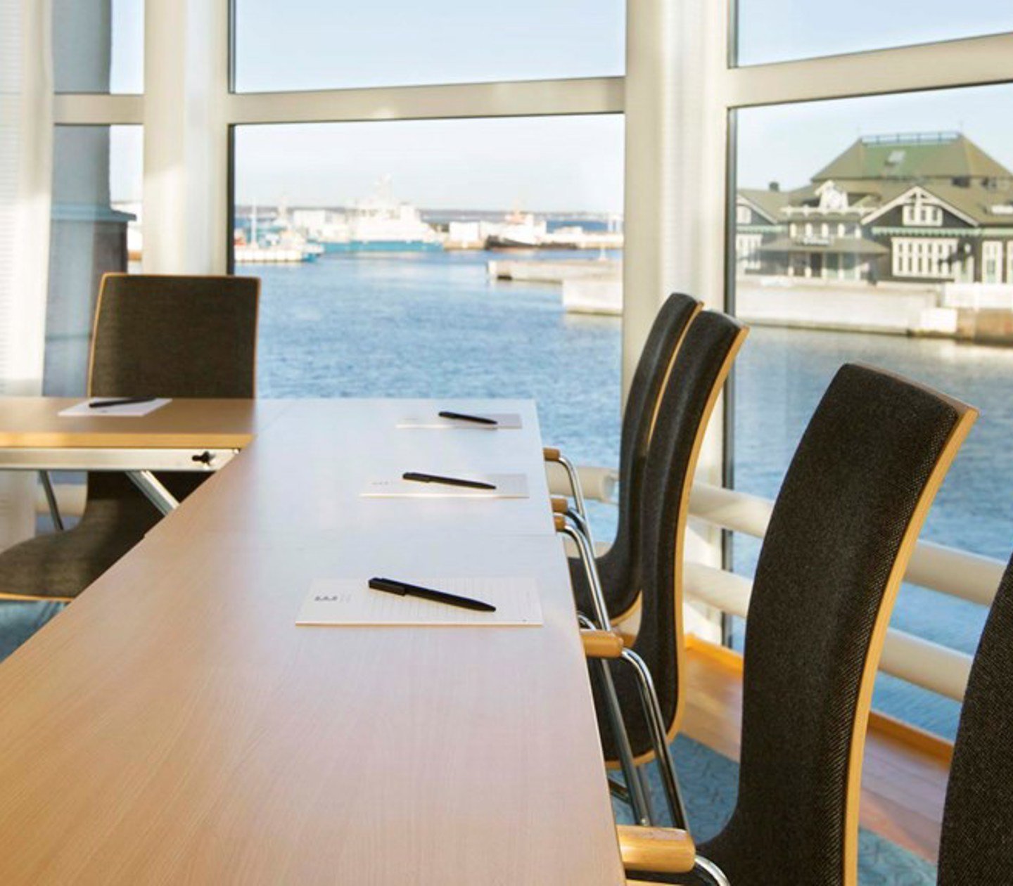Conference room with wooden table, dark chairs and large windows with a sea view