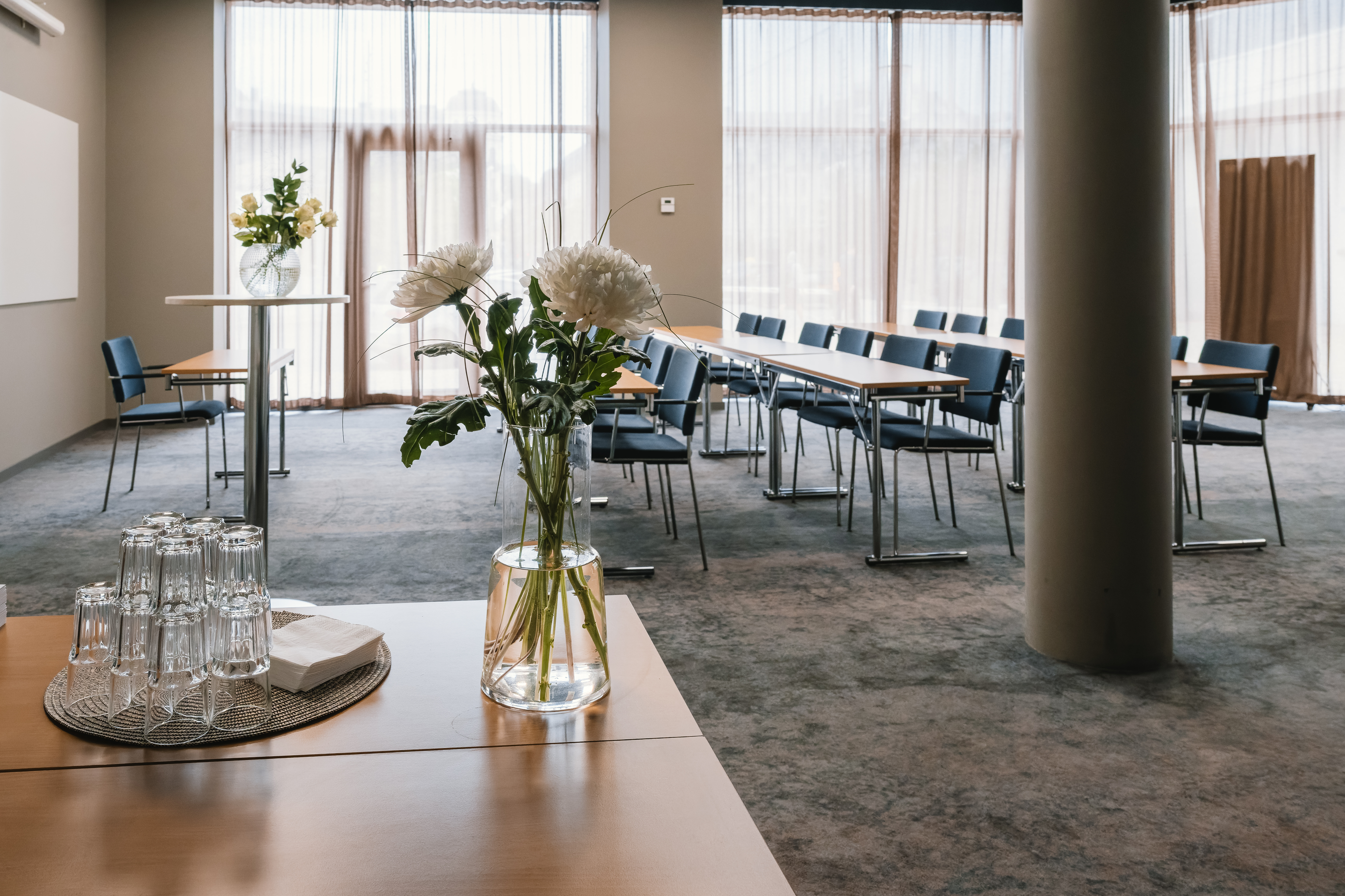 Conference room with board seating, wooden tables, large windows and colorful curtains