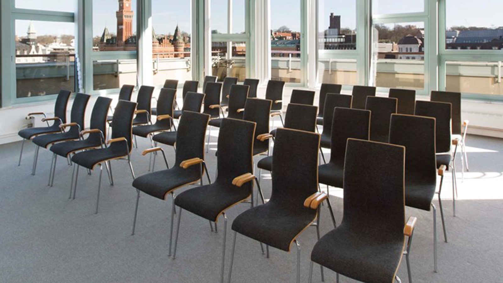 Conference room with lined up black chairs, gray carpet and large windows