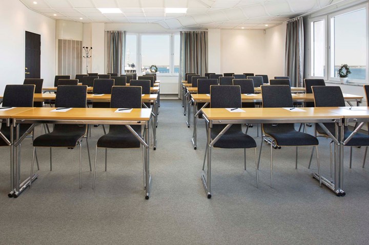 Conference room with lined up chairs, wooden tables and large windows with sea view