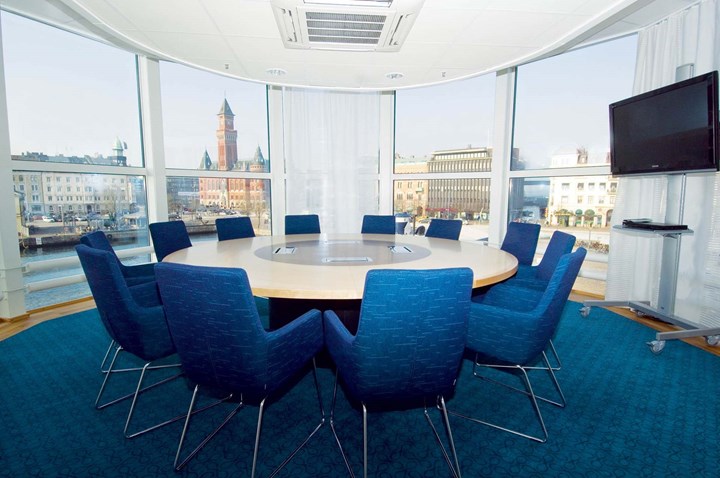 Conference room with round table, blue armchairs, blue carpet and large windows with a view