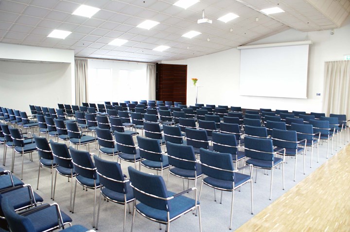 Conference room with lined up chairs, white walls and a projector