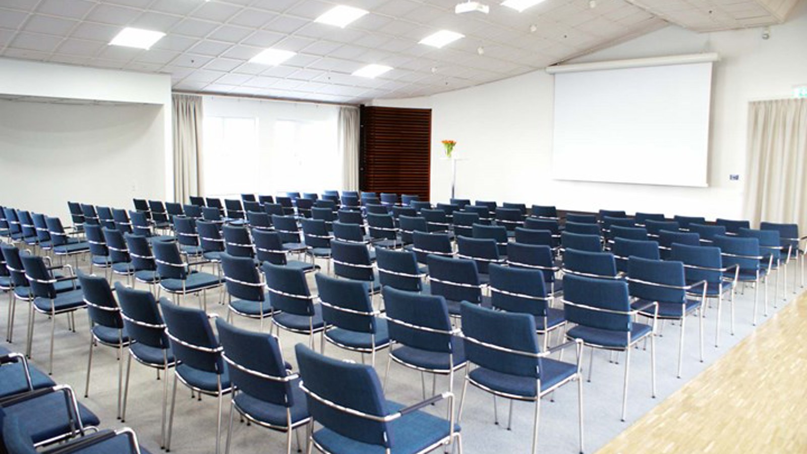 Conference room with lined up chairs, white walls and a projector