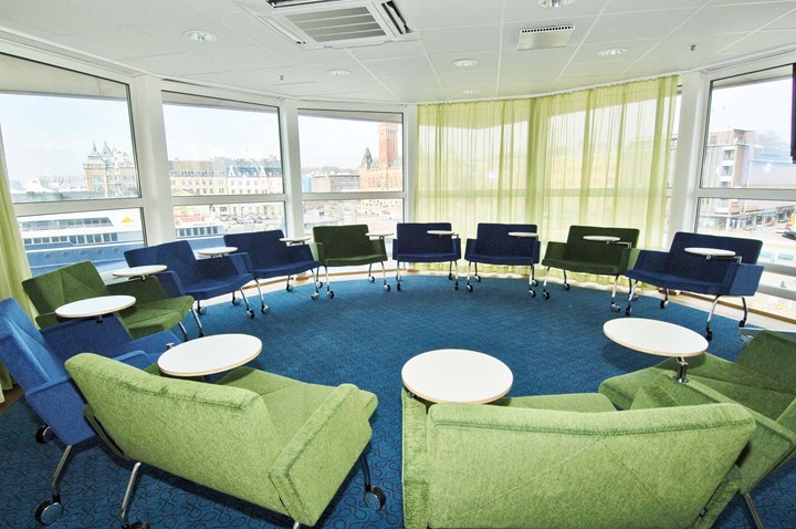 Room with green and blue armchairs in round seating and large windows with a view