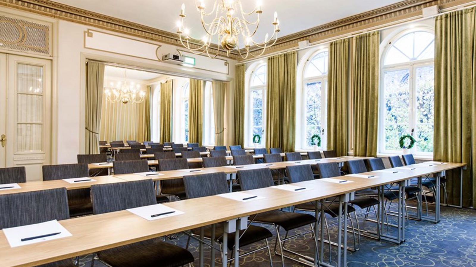 Conference room with lined up chairs, tables gold details and large windows