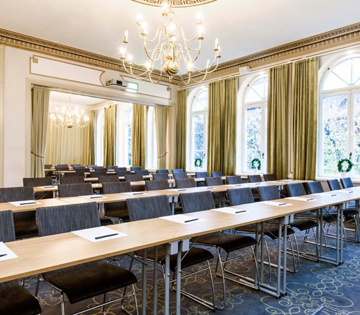 Conference room with lined up chairs, tables gold details and large windows