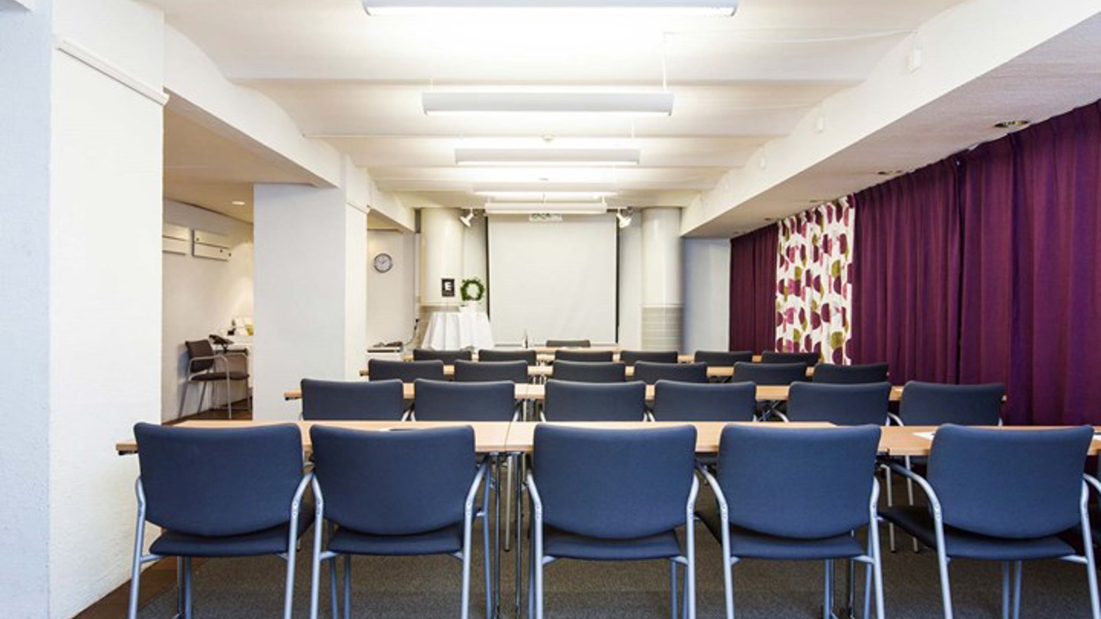Conference room with lined up blue chairs and purple drapery