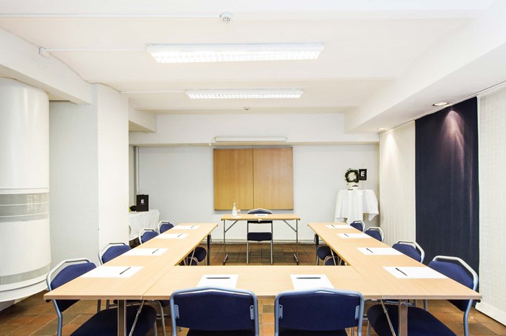 Conference room with U-shaped seating, white walls and light wooden table