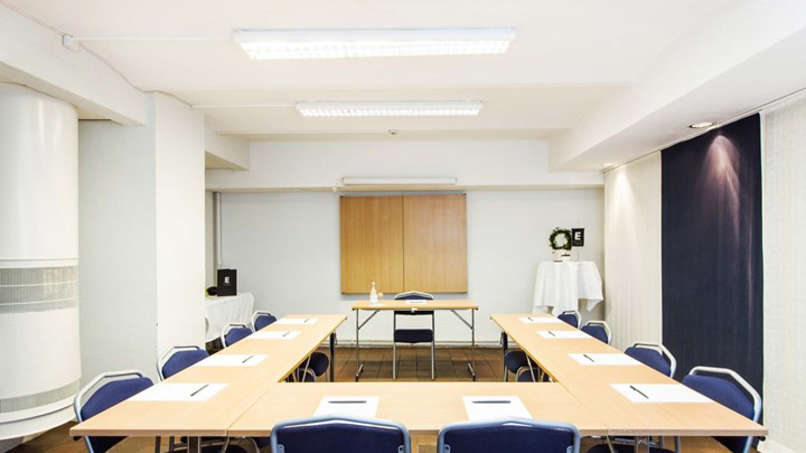Conference room with U-shaped seating, white walls and light wooden table