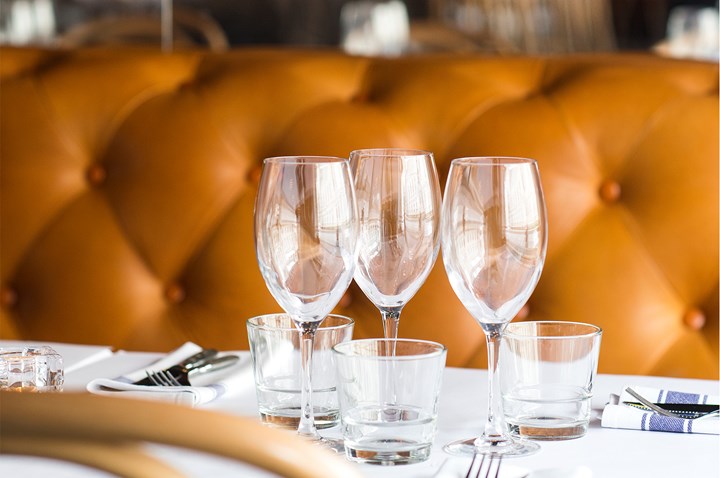 Three wine glasses on a table in front of a brown leather sofa