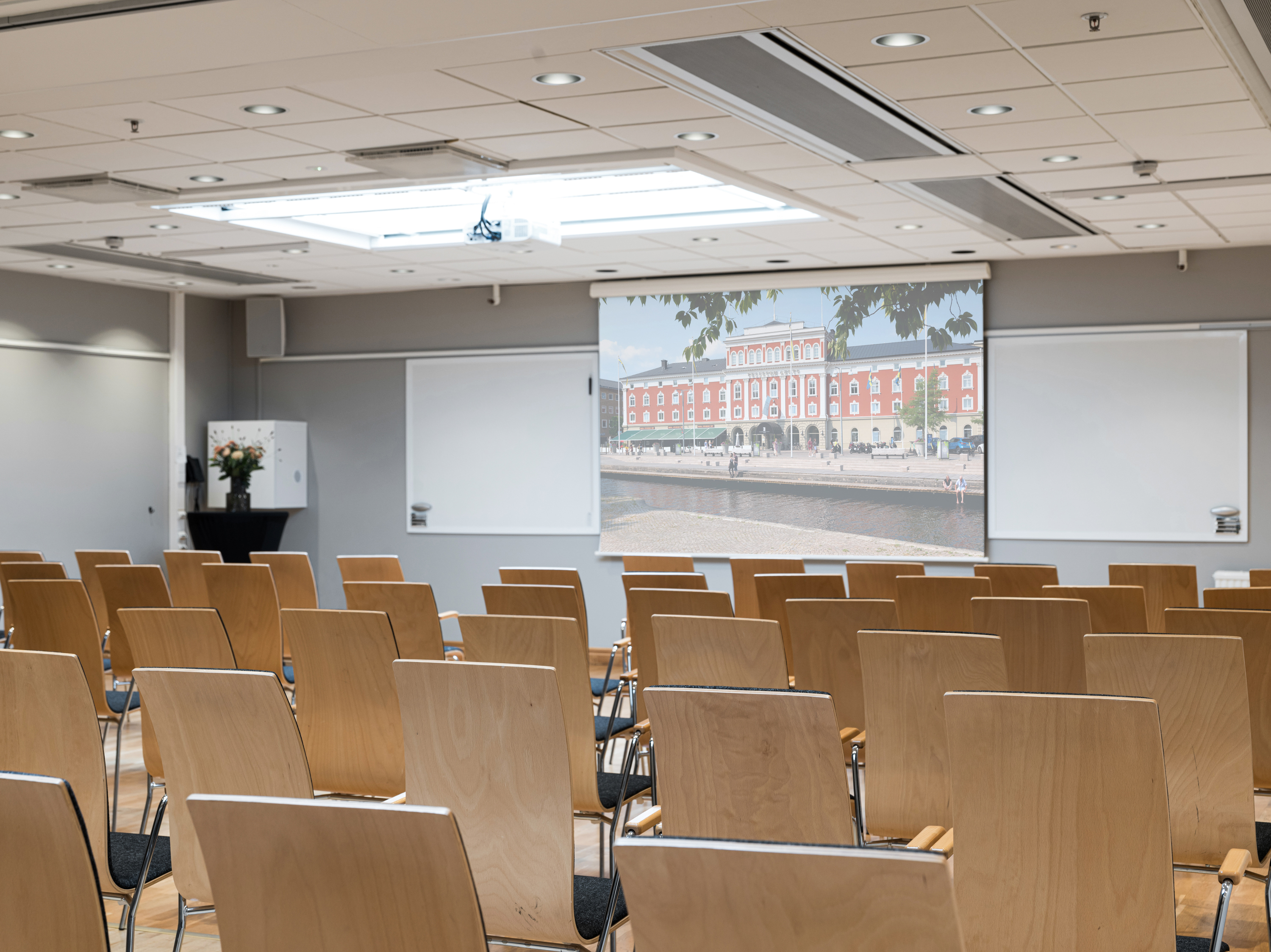 Conference room with wooden chairs and a large screen displaying a cityscape.