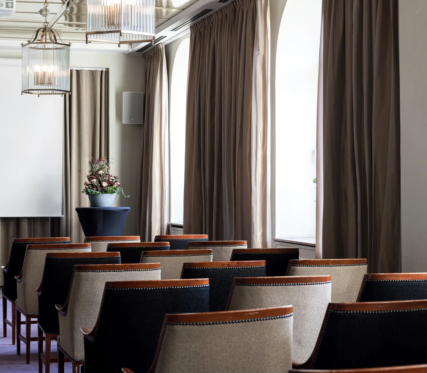 Conference room interior with rows of elegant chairs, a large window with curtains, and modern lighting.