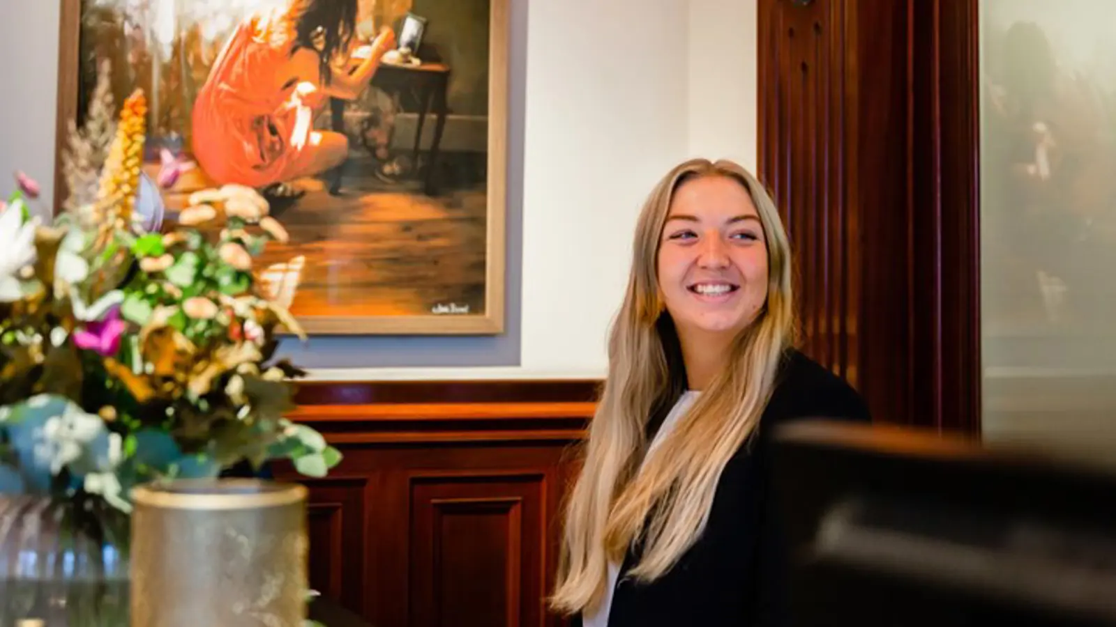 Miljöbild från hotellet med hotellpersonal, blommor och tavla