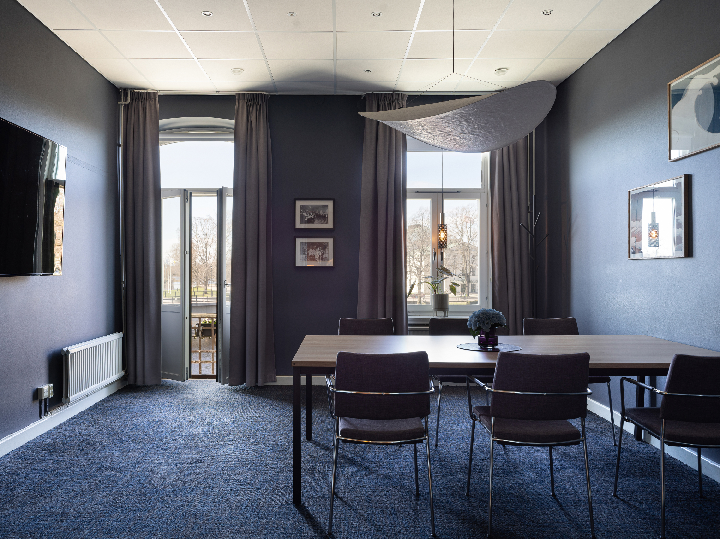 Boardroom with large windows, blue carpet and a TV screen