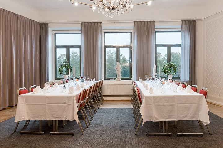 Room long tables, white tablecloths, large windows and draperies