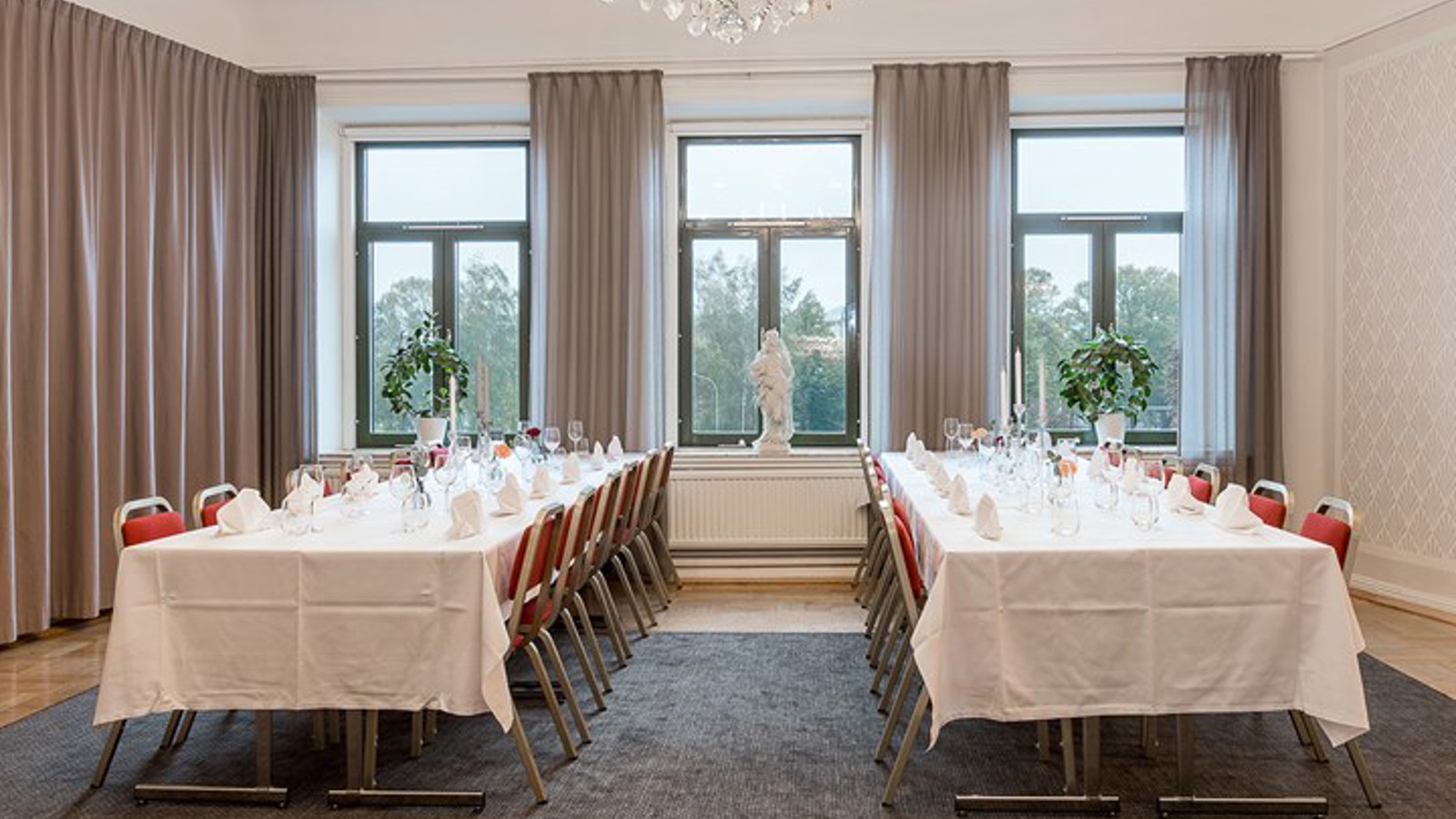 Room long tables, white tablecloths, large windows and draperies