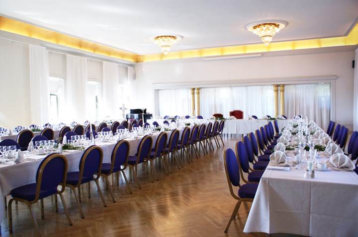 Room with long tables, white tablecloths and large windows