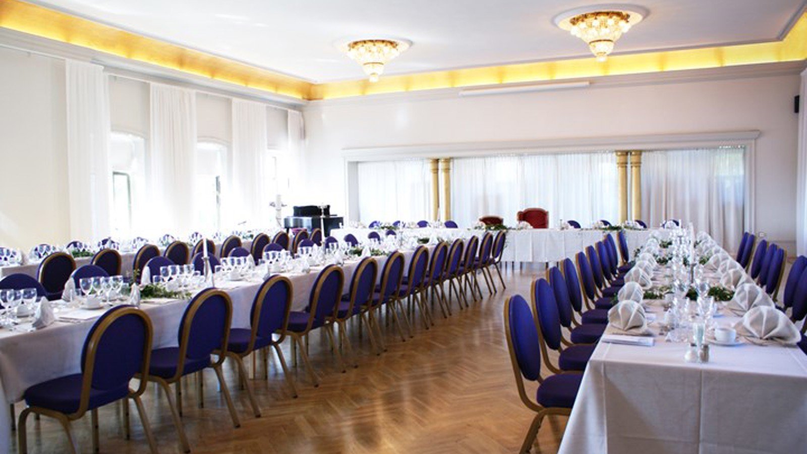 Room with long tables, white tablecloths and large windows