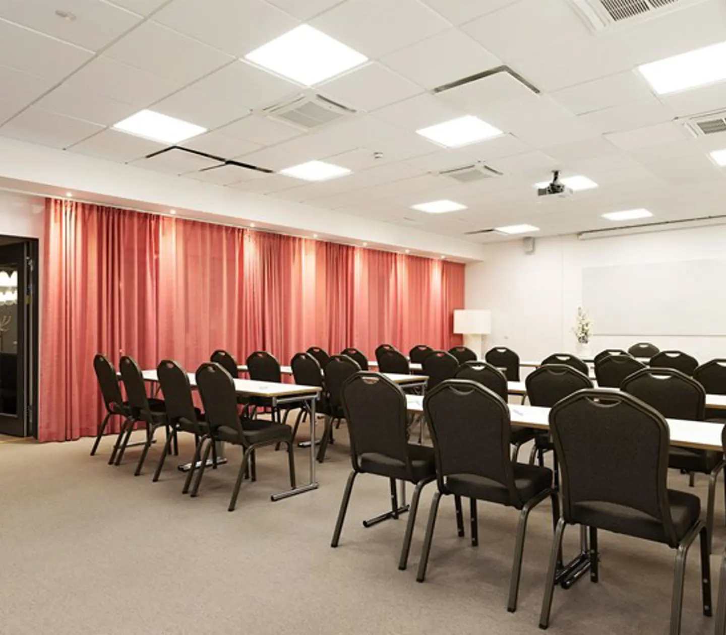 Conference room with lined up chairs, red drapery and light walls