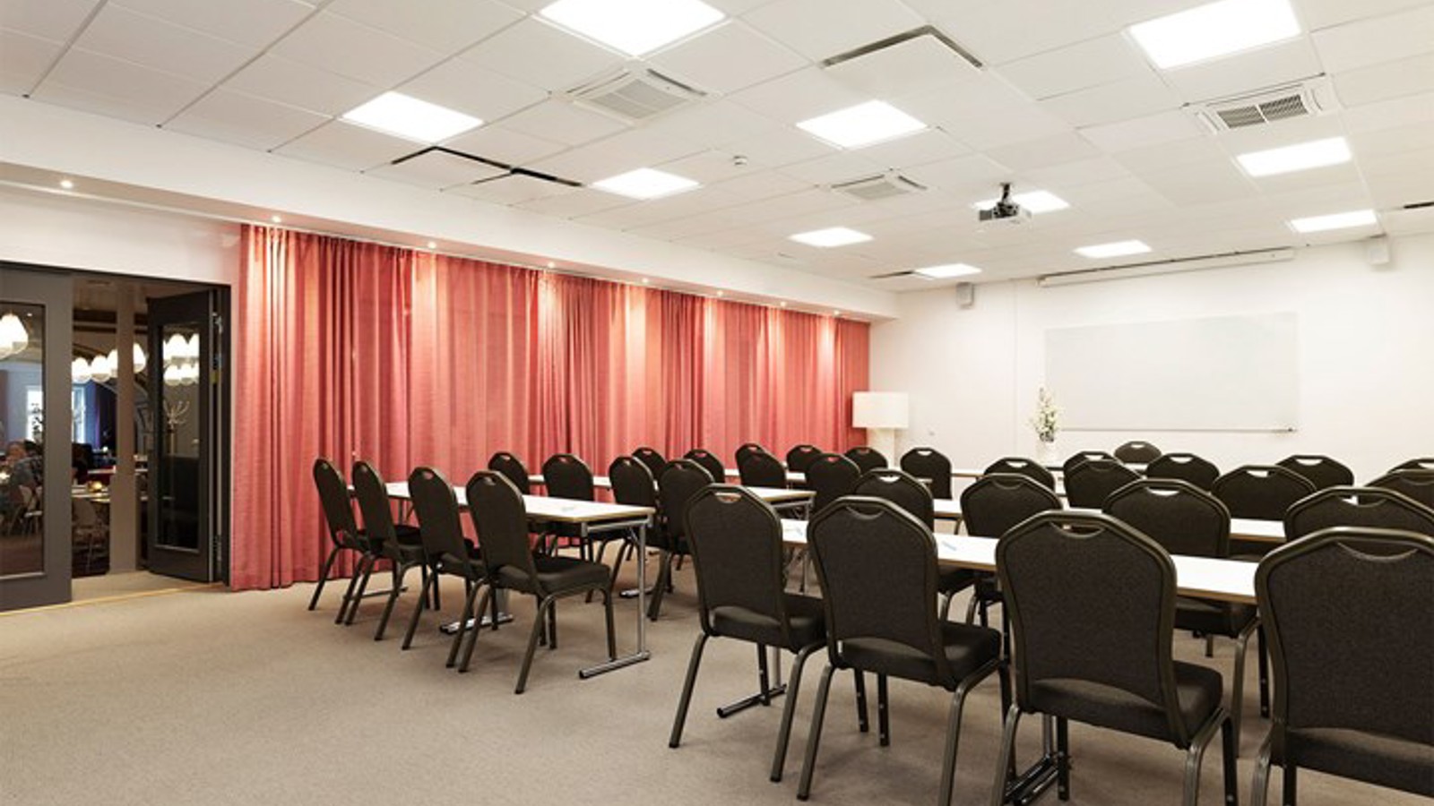 Conference room with lined up chairs, red drapery and light walls