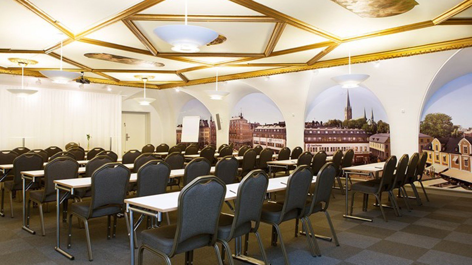 Conference room with lined up chairs, light ceiling with gold details and dark floor