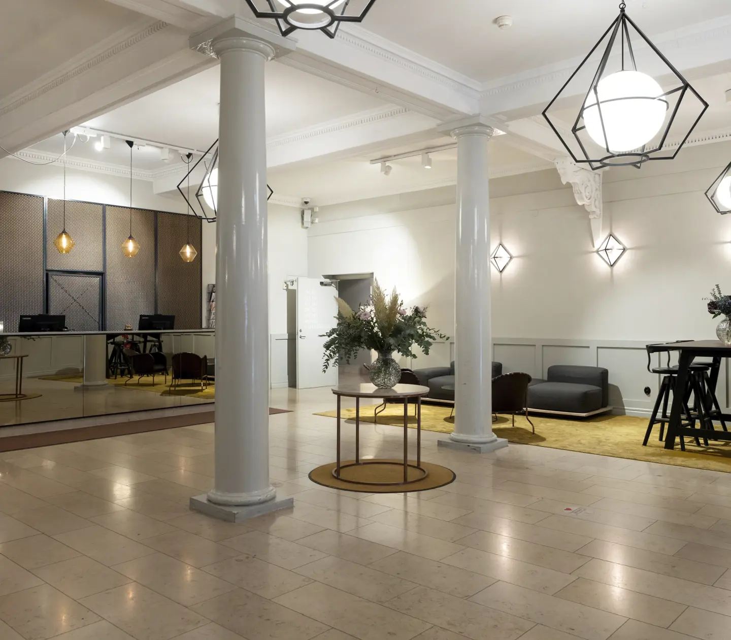 Modern hotel lobby with elegant lighting, a mirrored front desk, contemporary seating area, and stylish decor for a welcoming atmosphere.