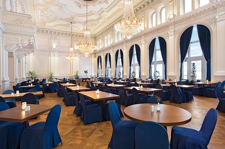 Stor festlokal med kristallkronor, stukaturer, vita väggar och blå detaljer