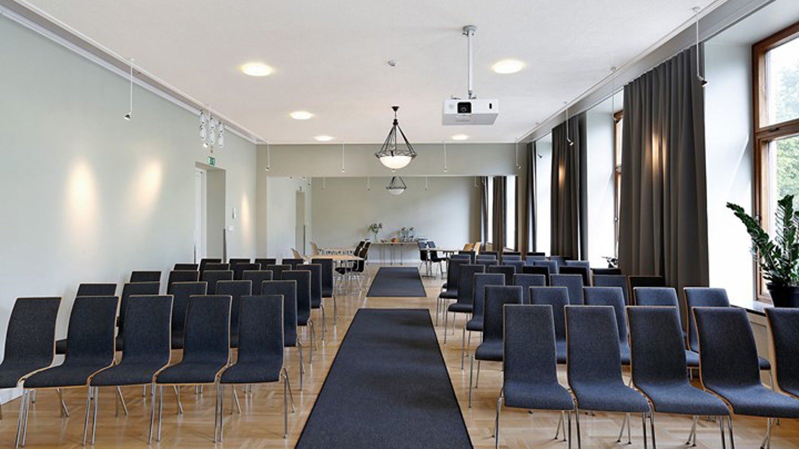 Conference room with lined up dark chairs, light walls and large windows