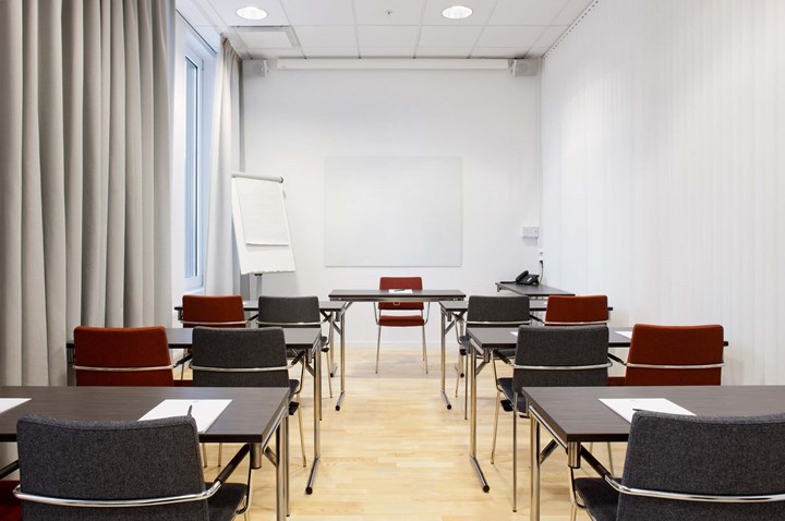 Conference room with lined up chairs, black tables and white walls