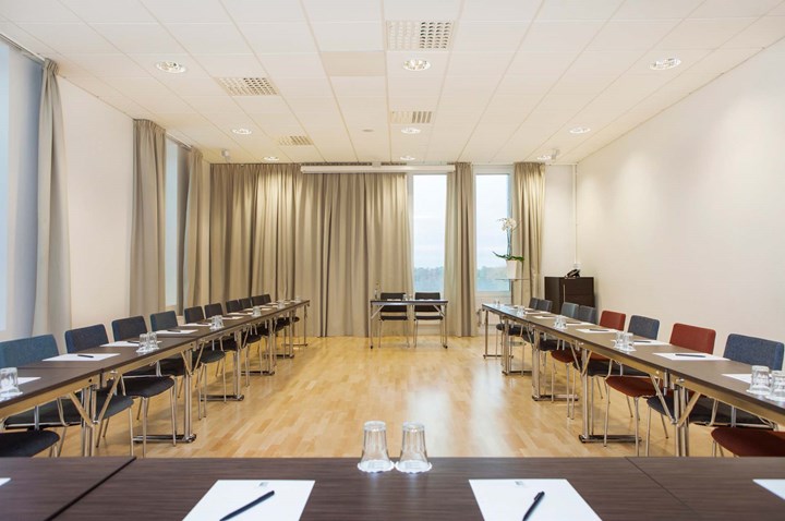 Large conference room with U-shaped seating, light walls and wooden floors