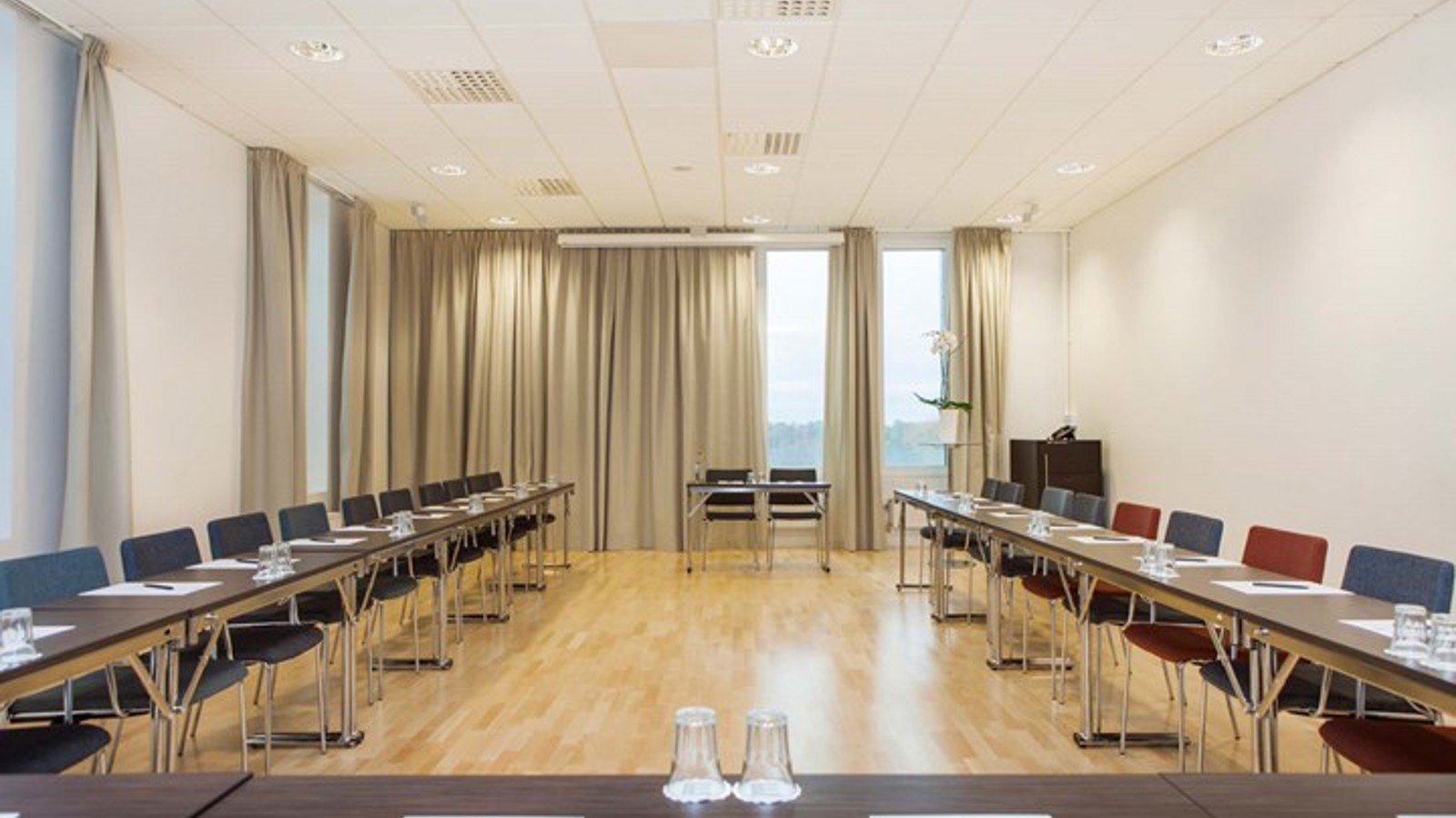 Large conference room with U-shaped seating, light walls and wooden floors