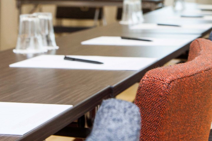 Close-up of brown conference table with pens and pads