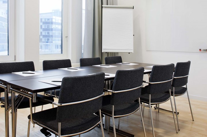 Conference room with board seating, brown table, dark chairs, white walls