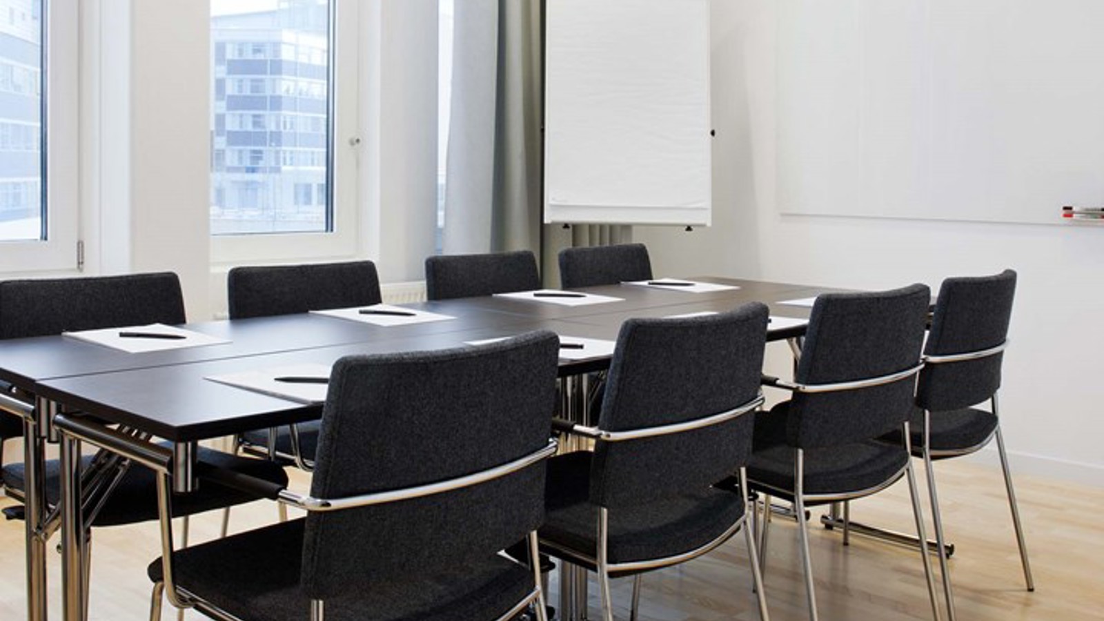 Conference room with board seating, brown table, dark chairs, white walls