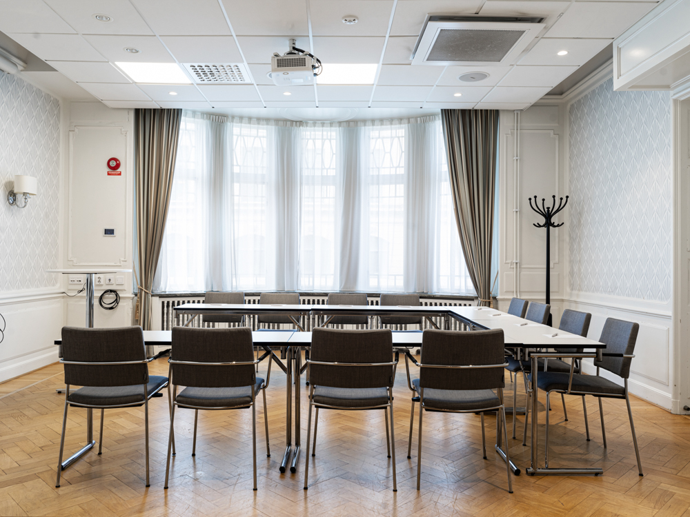 Konferensrum med styrelsesittning, grå stolar, vita väggar