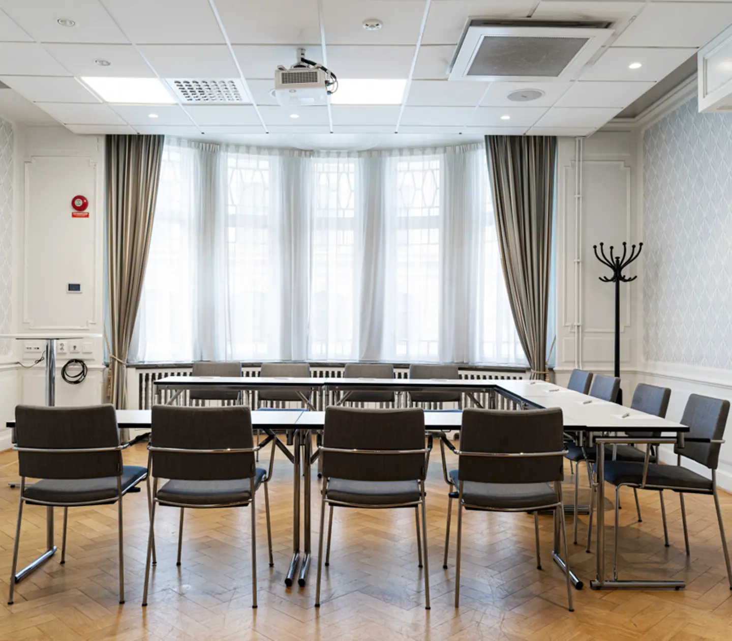 Konferensrum med styrelsesittning, grå stolar, vita väggar