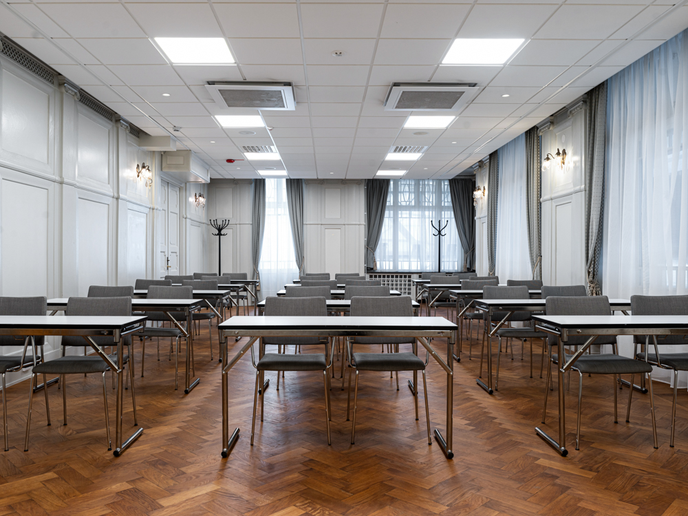 Konferensrum med skolsittning, grå stolar, vita väggar och stora fönster