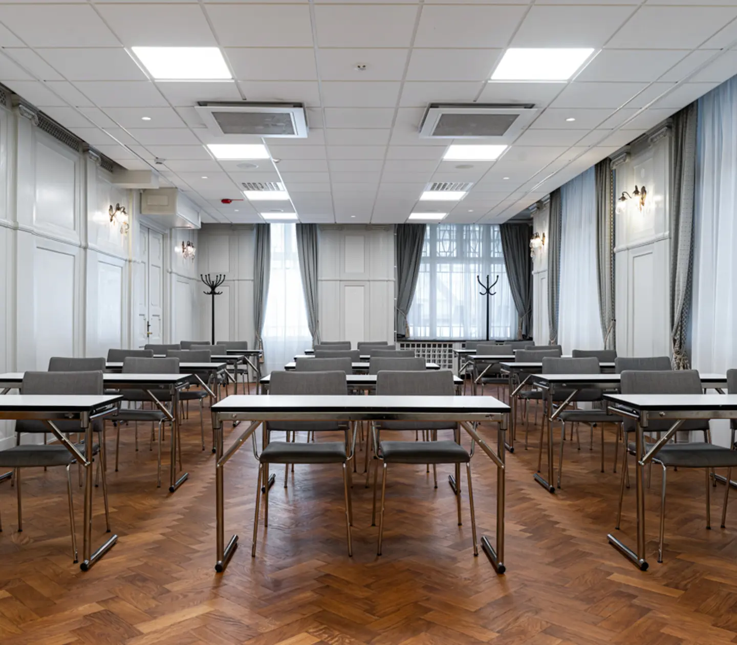 Konferensrum med skolsittning, grå stolar, vita väggar och stora fönster