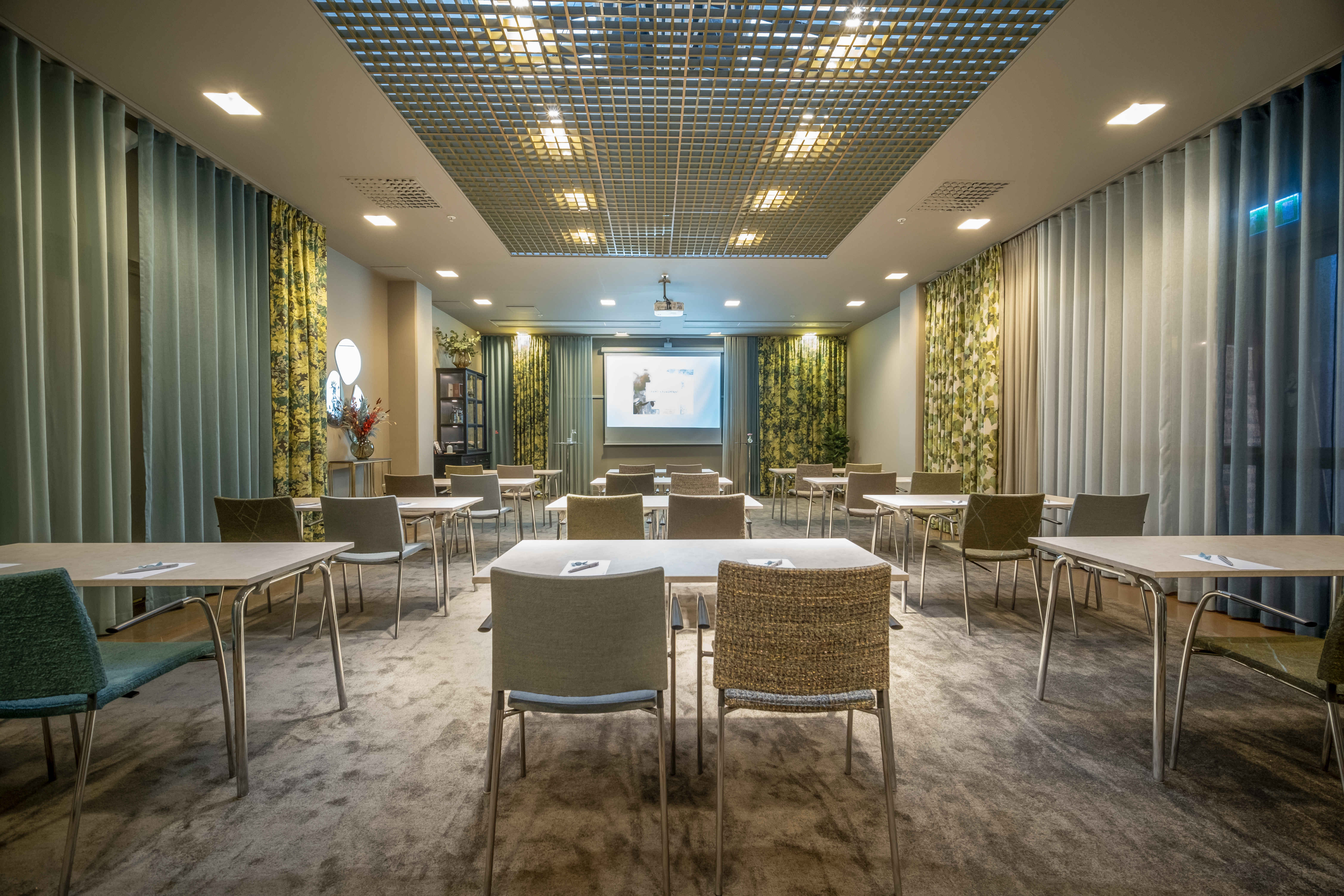 Conference room with lined up red chairs, green walls and yellow draperies