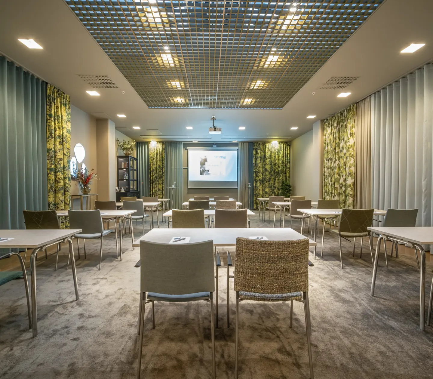 Konferensrum med skolsittning, röda stolar, gröna väggar och gula draperier