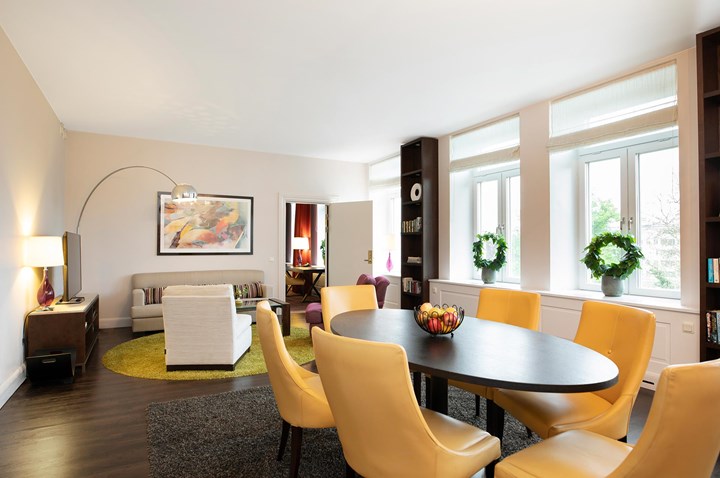 Conference room with board seating, yellow armchairs, a sofa group and large windows