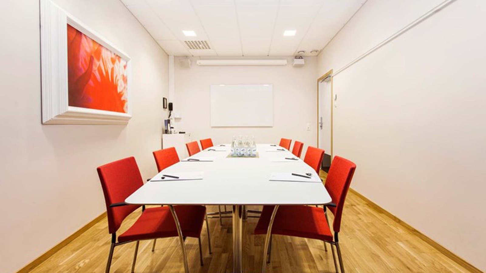 Board room with white table, red chairs and white walls