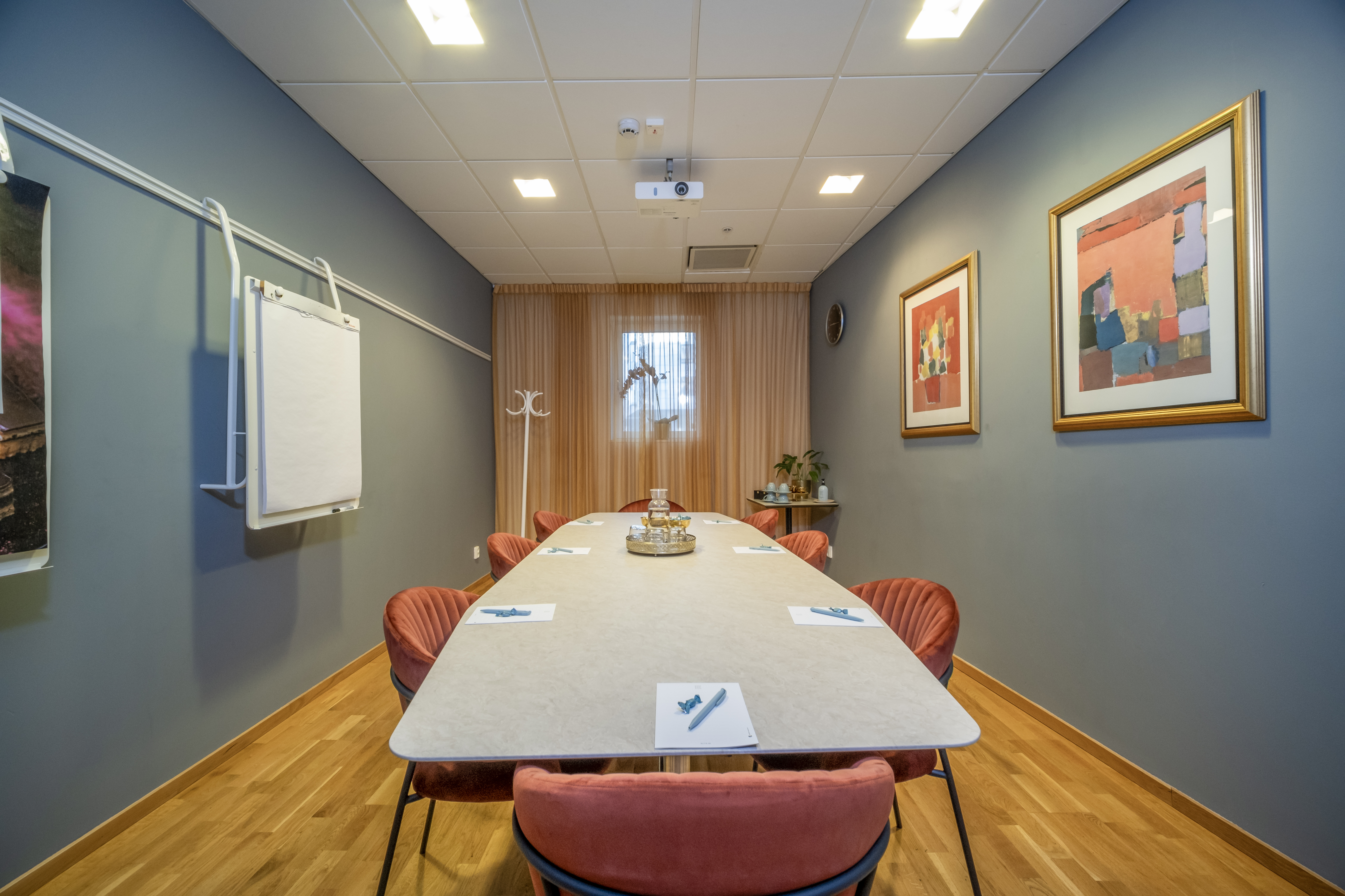 Board room with white table, red chairs and white walls