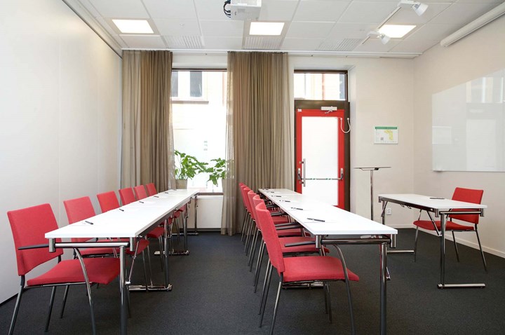 Conference room with lined up chairs, white tables, red chairs and large window