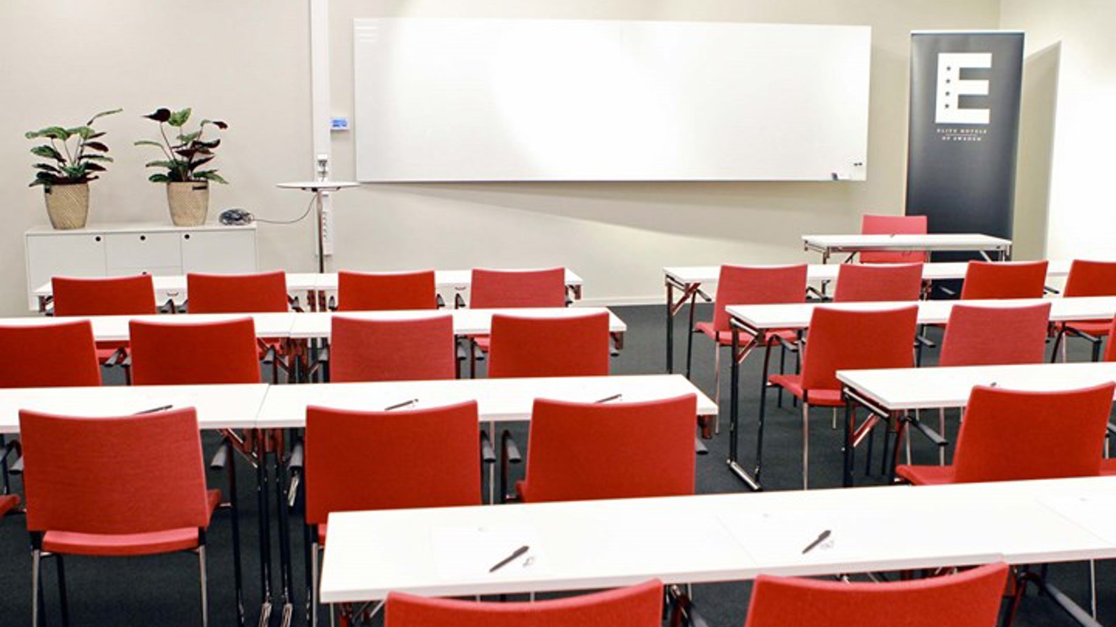 Conference room with school seating, white tables, red chairs