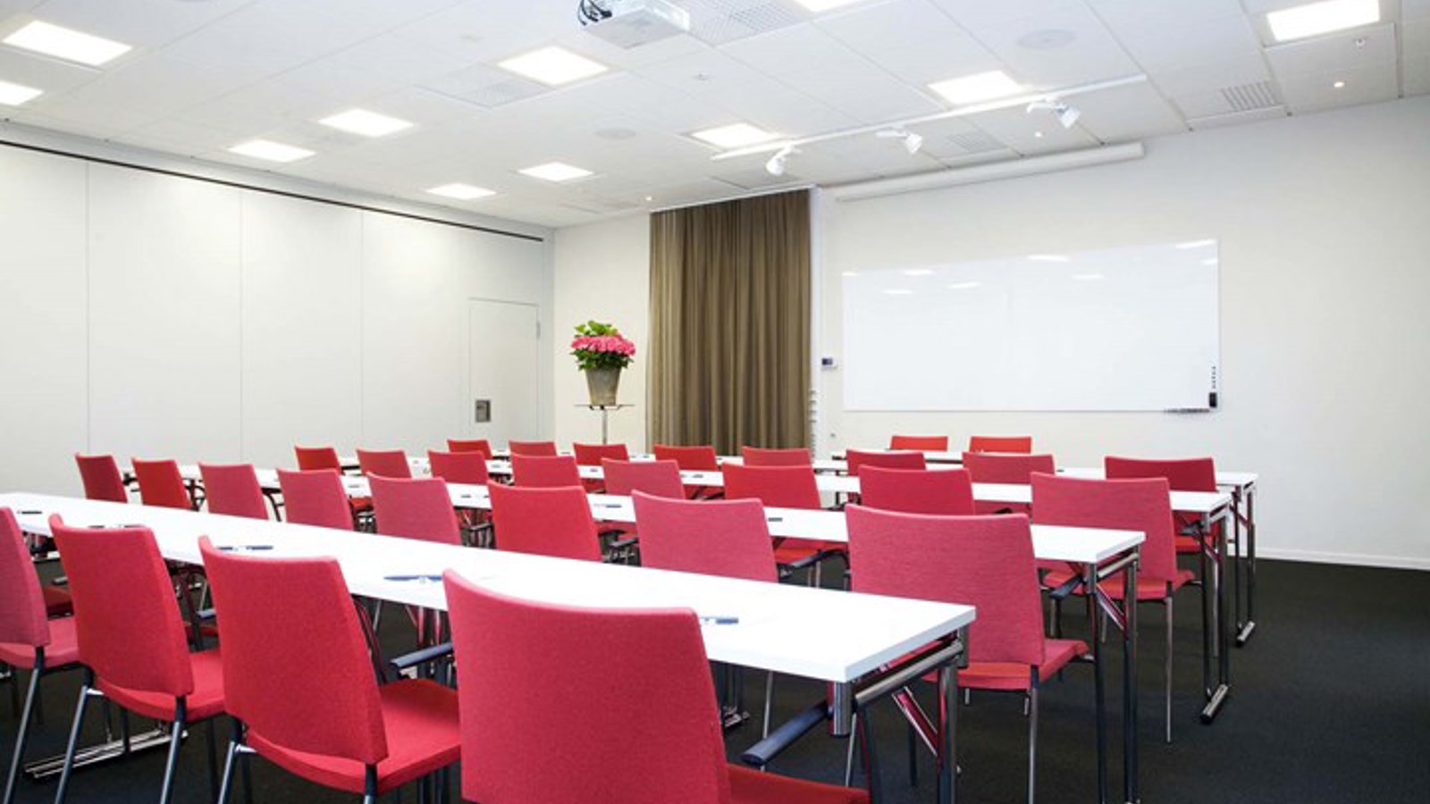 Conference room with white tables, red chairs, black floor
