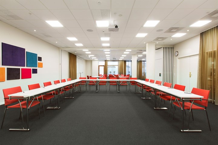 Conference room with u-shaped seating, black floor, white table, red chairs