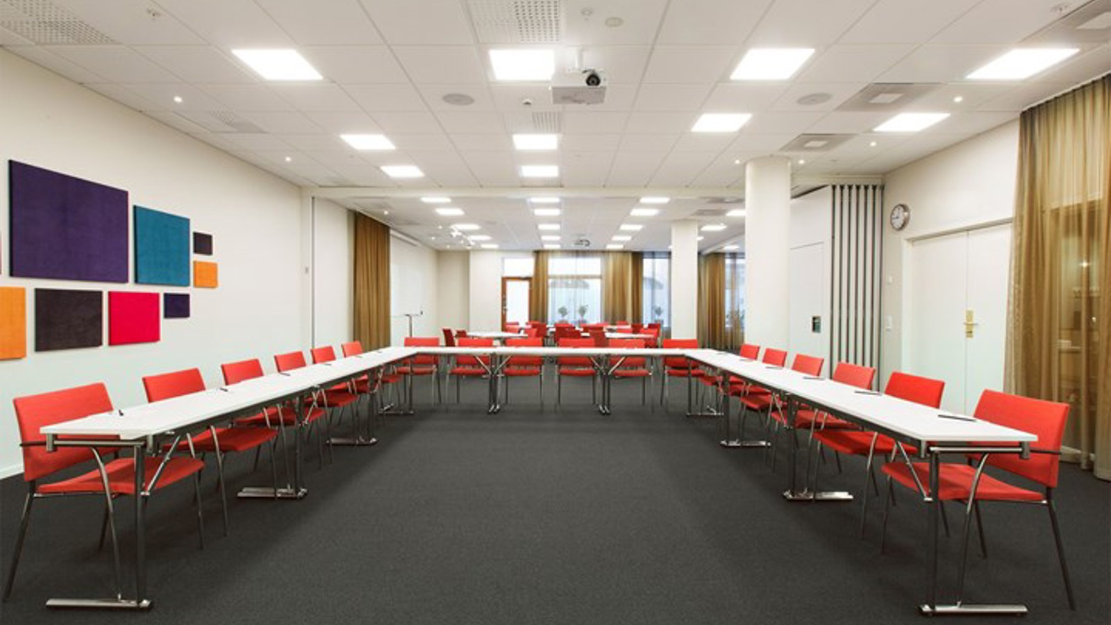 Conference room with u-shaped seating, black floor, white table, red chairs