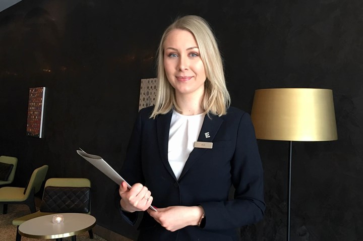 Image of hotel staff with brochure in hand and a dark wall behind
